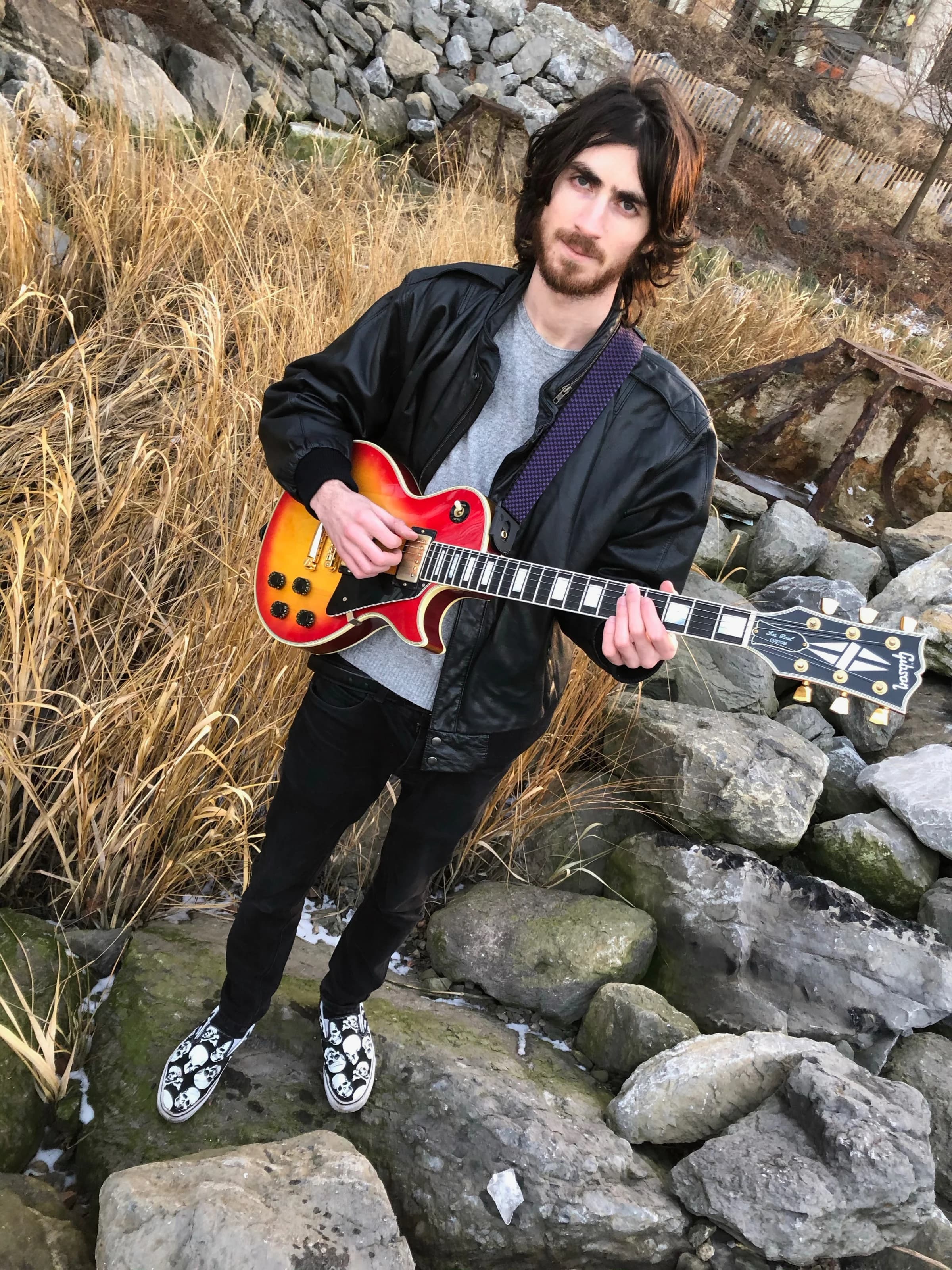 Warren Galea holding a guitar outdoors